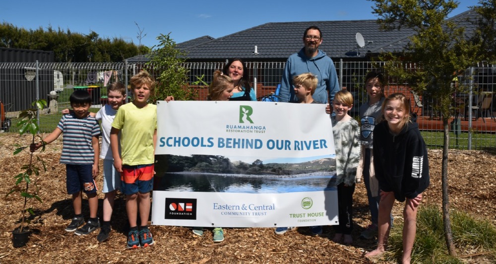 Te Kura O Papatuanuku Wairarapa Earth School students holding a "Schools Behind Our River" banner